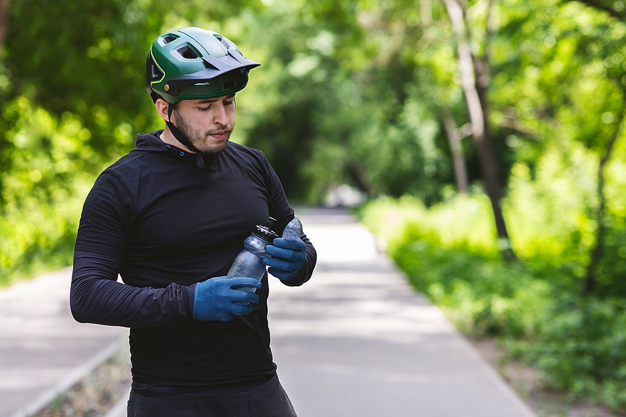 Man biker i n helmet drinking water - best cycling hydration pack