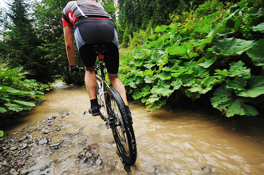 Best mountain bike shoes. young man drive mountain bike over water river